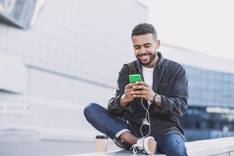 Young handsome men using smartphone in a city. Smiling student m